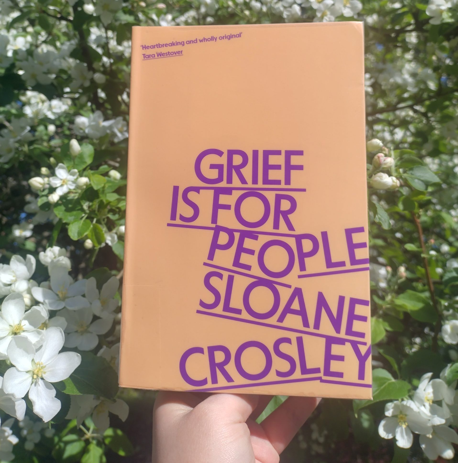 Grief is for people photographed in front of a blossoming apple tree